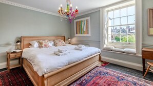 Un dormitorio con una cama grande, una araña, una ventana con vistas y una alfombra.