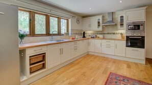 A kitchen with white cabinets, a wooden countertop, a sink, a stove, and a microwave. - 3 Bed in Fakenham (oc-1315) (Thursford)