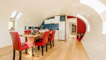A modern kitchen with a curved ceiling, a dining area with red chairs, and a visible kitchen counter.