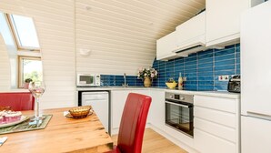 A compact kitchen with a dining area, featuring a microwave, oven, and a blue tiled backsplash.