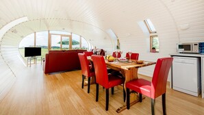 A dining area with a wooden table, red chairs, and a view of the outdoors.