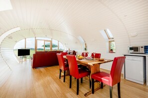 A dining area with a wooden table, red chairs, and a view of the outdoors.