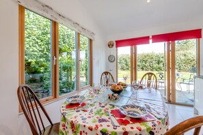 A dining area with a table set for four, surrounded by chairs, large windows, and a view of greenery. - 2 Bed in Stelling Minnis (oc-ek716) (Lyminge)