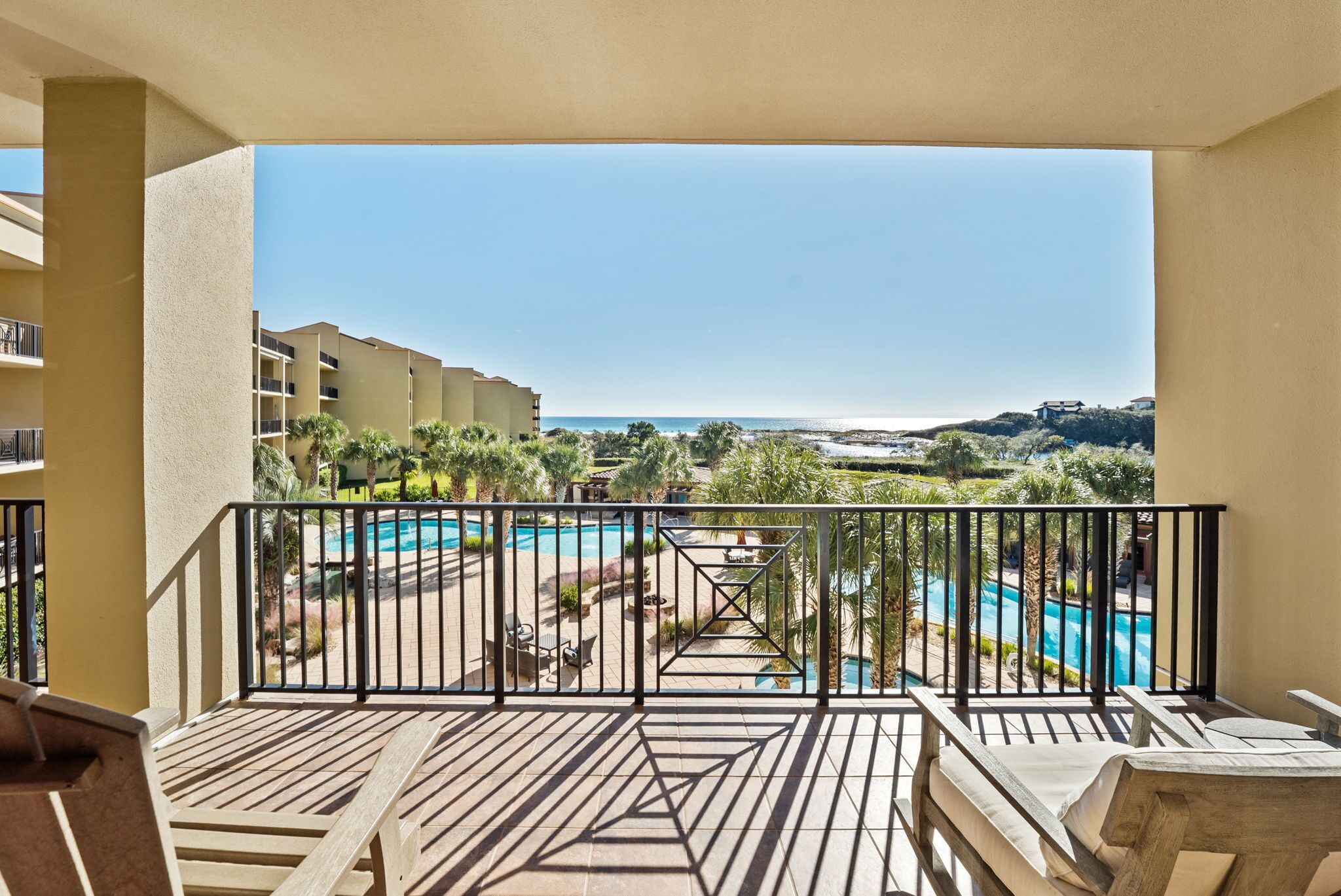 Ein Balkon mit Blick auf ein Schwimmbad und einen Strand.