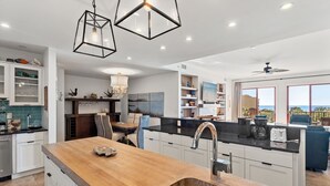 A modern kitchen with a wooden island, white cabinetry, and pendant lighting. - Wonderful Condo on 30A! (Santa Rosa Beach)