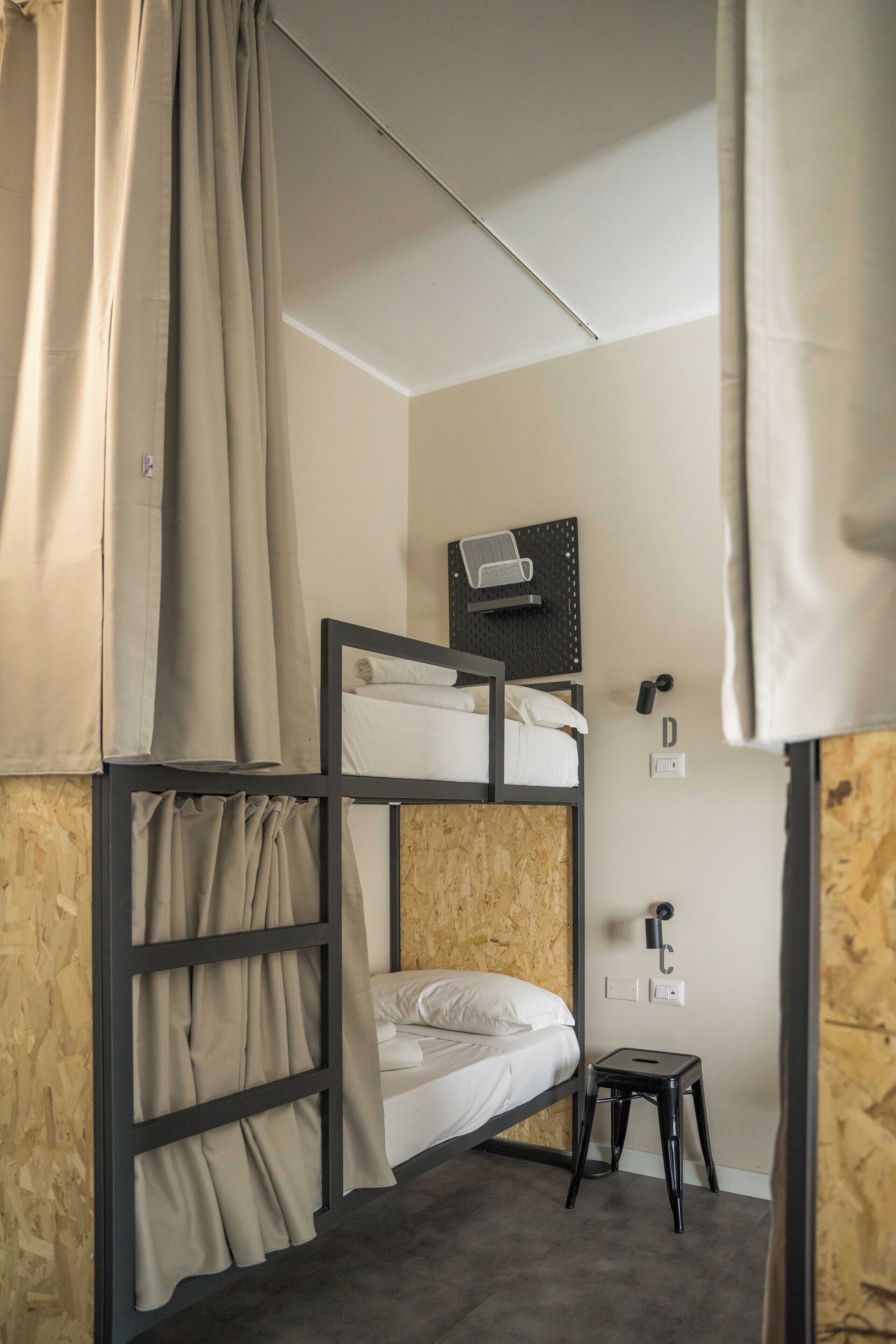A bunk bed room with a small stool, a wall-mounted heater, and a power outlet.