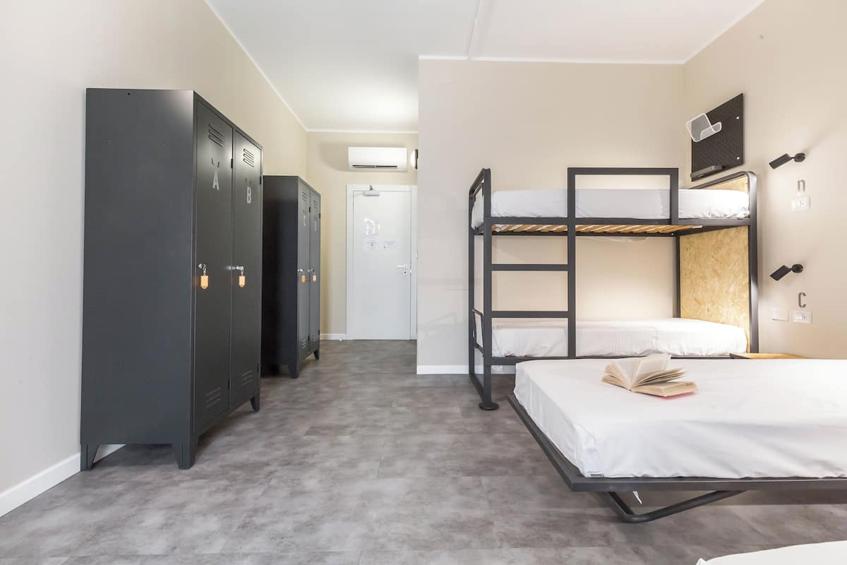 A dormitory room with bunk beds, a wardrobe, and a door leading to a bathroom.