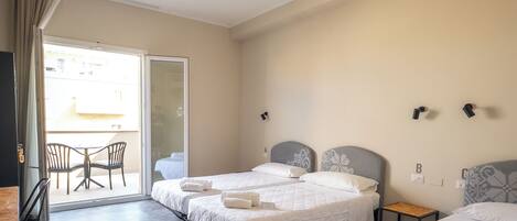 Una habitación de hotel con dos camas, una mesa pequeña, sillas y un balcón.