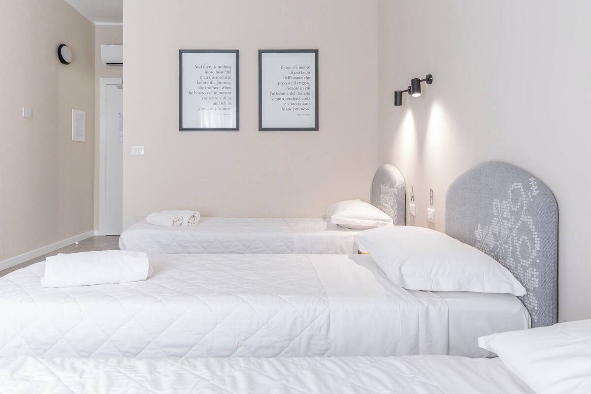 A hotel room with two beds, a large window, and a wall-mounted air conditioning unit.
