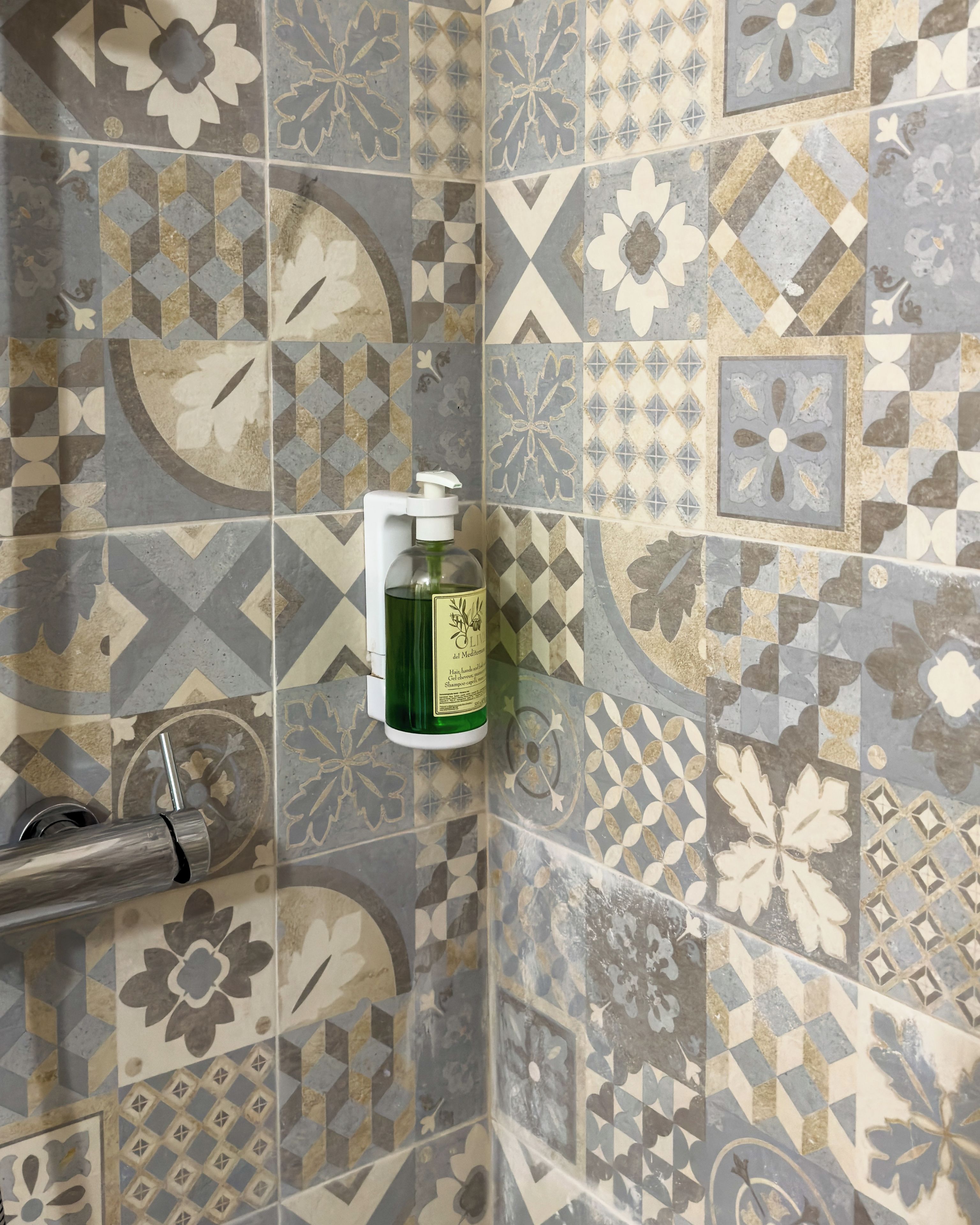 Une salle de bain avec un mur recouvert de carreaux aux motifs géométriques et floraux.