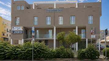 Un hotel con un letrero que dice 'Piccolo Catalunya Hotel' y un letrero que indica 'Conf. Int. Alghero'.