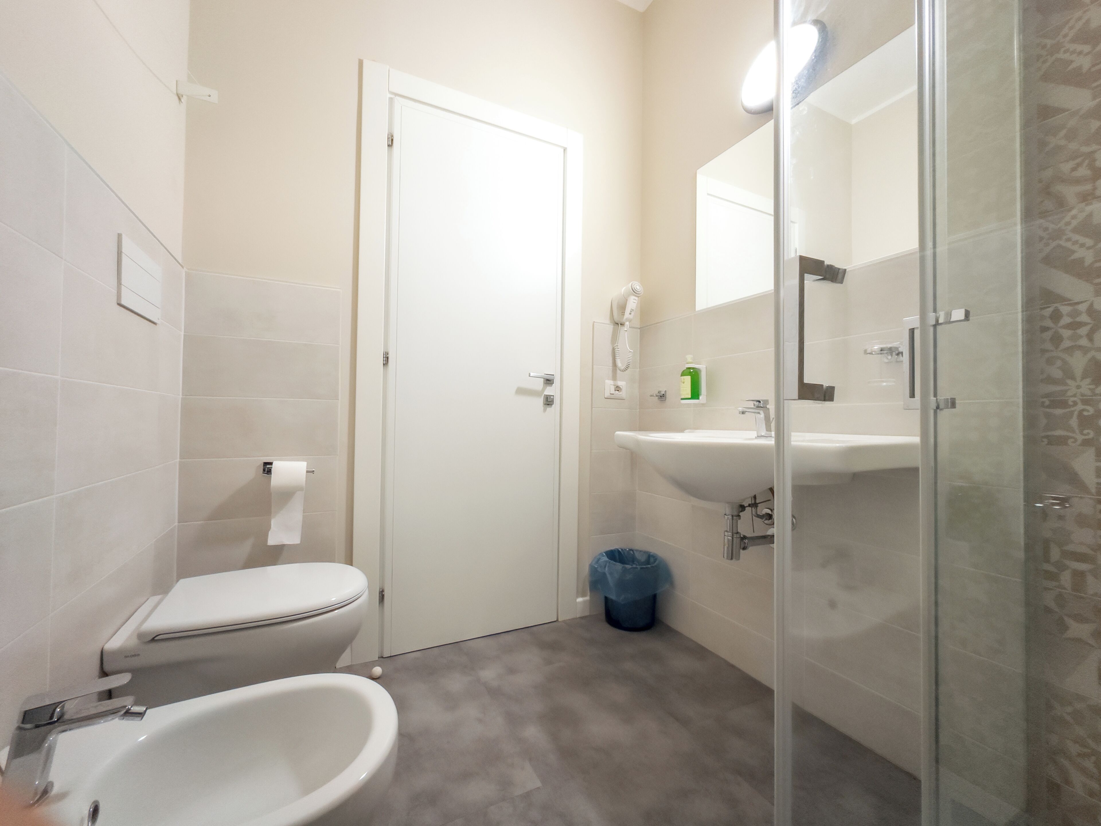 A bathroom with a toilet, bidet, sink, and glass shower enclosure.