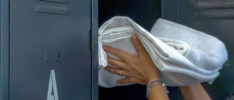 Una persona guardando una toalla blanca en un locker metálico con una 'A' grande.