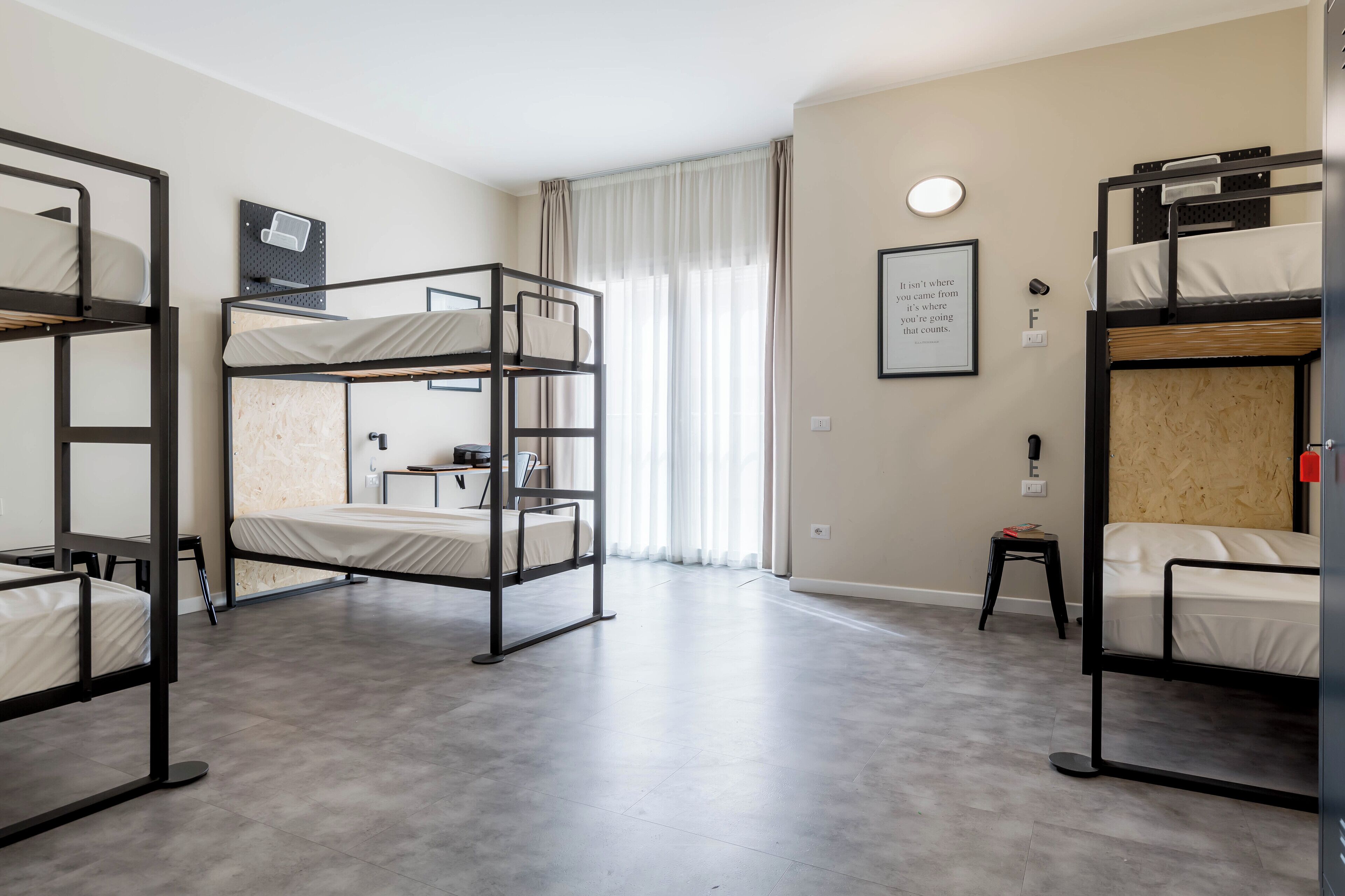 A dormitory room with bunk beds, a small desk, and a chair.