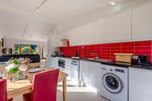 A modern kitchen with white cabinets, a red backsplash, and a built-in washing machine. - 2 Bed in Stelling Minnis (oc-ek715) (Lyminge)
