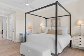 A four-poster bed with a white canopy, a bedside table with a lamp, and a nightstand with a lamp. - Amazing Condo on the Beach on 30A! (Santa Rosa Beach)