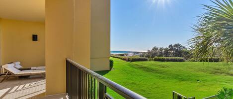 A balcony with a sun lounger and a view of a green lawn and distant landscape.