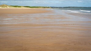 A wide sandy beach with gentle waves and a clear sky. - 2 Bed in Amble (oc-l32947) (Amble)