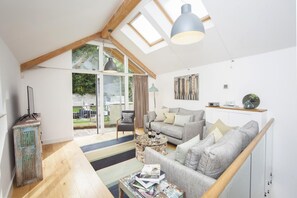A spacious living area with a high ceiling, a sofa set, a coffee table, and a view through a glass door to an outdoor patio. - 2 Bed in Bath (oc-bhr9) (Bath)