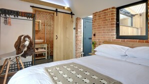 A bedroom with a large bed, a wooden wardrobe, a brick wall, and a window. - 1 Bed in Stone (oc-tn618) (Stone in Oxney)