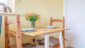 Una mesa de comedor con sillas, un jarrón con flores y un cuadro en la pared.