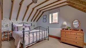 Ein Schlafzimmer mit Bett, Schminktisch, Kommode und Fenster.