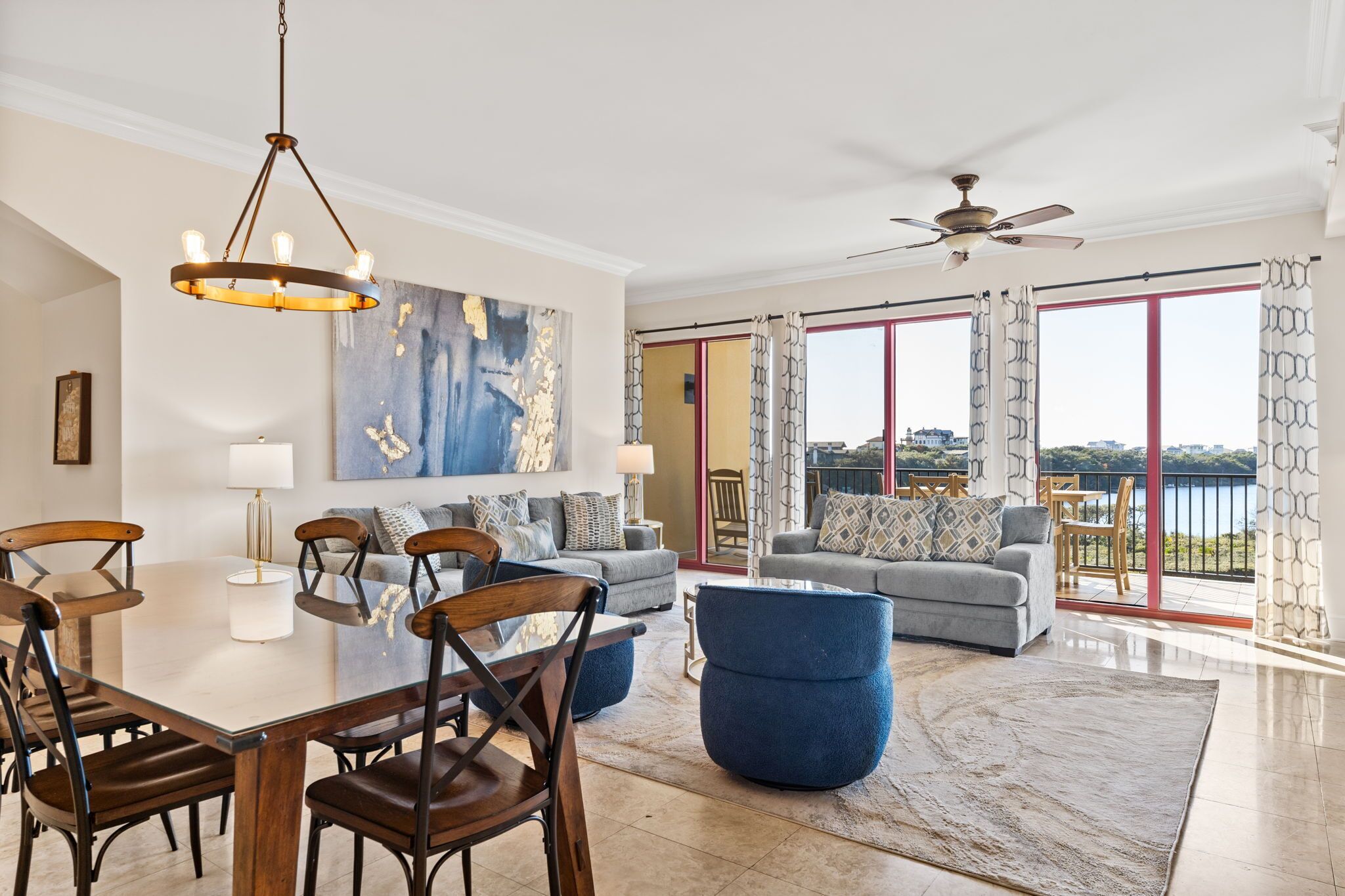 A spacious living area with a dining table, chairs, sofas, and a large window with a view.