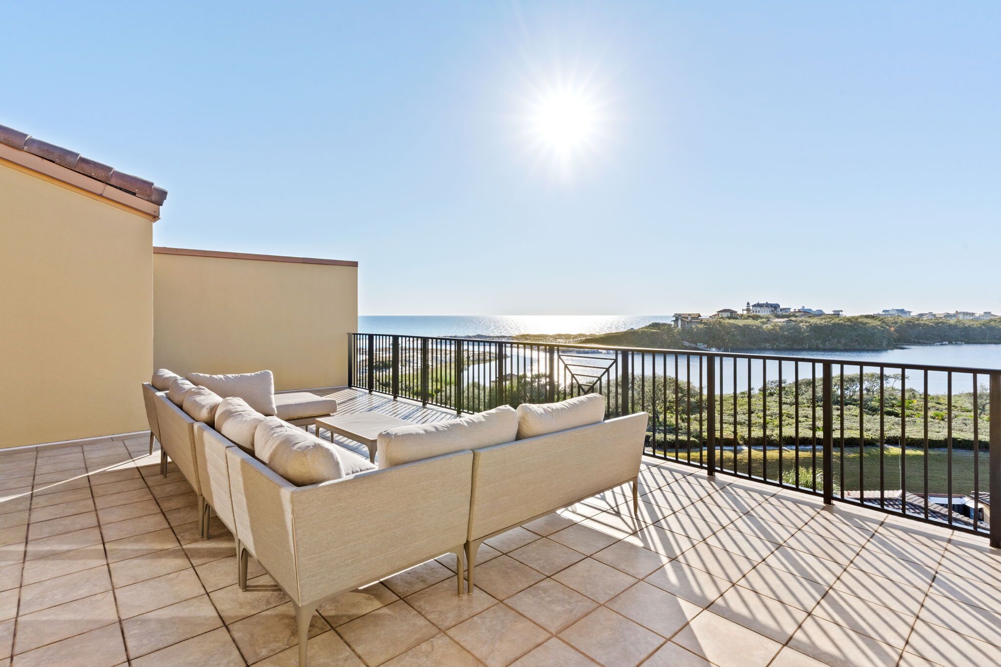 A balcony with a sofa and table, overlooking a body of water and greenery.