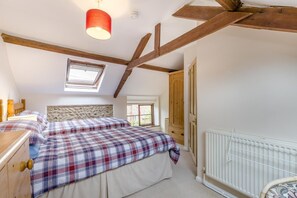A bedroom with a sloped ceiling, a skylight, a wooden headboard, a double bed with plaid bedding, a wooden dresser, and a radiator. - 2 Bed in Field Dalling (oc-421) (Field Dalling)