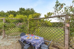 An outdoor dining area with a table set for two, surrounded by a wooden trellis and a lattice fence. - 2 Bed in Field Dalling (oc-421) (Field Dalling)