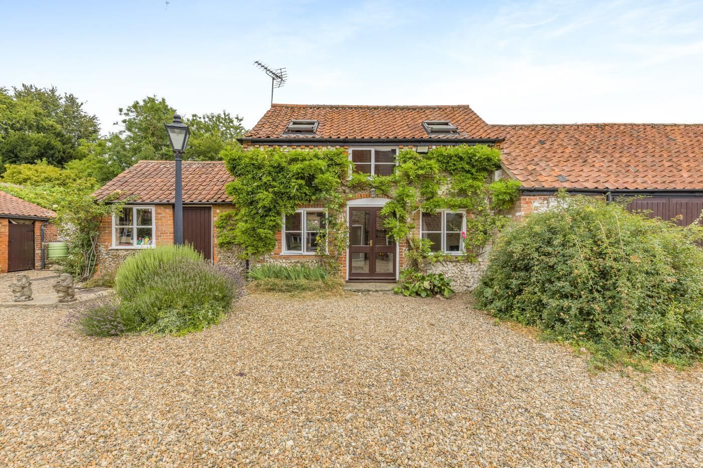A two-story house with a gravel driveway, a front door, and a small garden area.