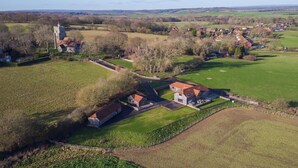 An aerial view of a rural property with a large house, a tower, and surrounding fields. - 2 Bed in Tenterden (oc-tn606) (Stone in Oxney)