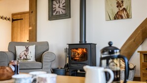 A cozy living room with a fireplace, a sofa with a rabbit pillow, a clock on the wall, and a painting of a rabbit. - 2 Bed in Tenterden (oc-tn606) (Stone in Oxney)