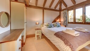 A bedroom with a bed, bedside table, lamp, and a window with curtains. - 2 Bed in Tenterden (oc-tn606) (Stone in Oxney)