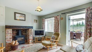 Un salon chaleureux avec une cheminée, un téléviseur et des fauteuils confortables.
