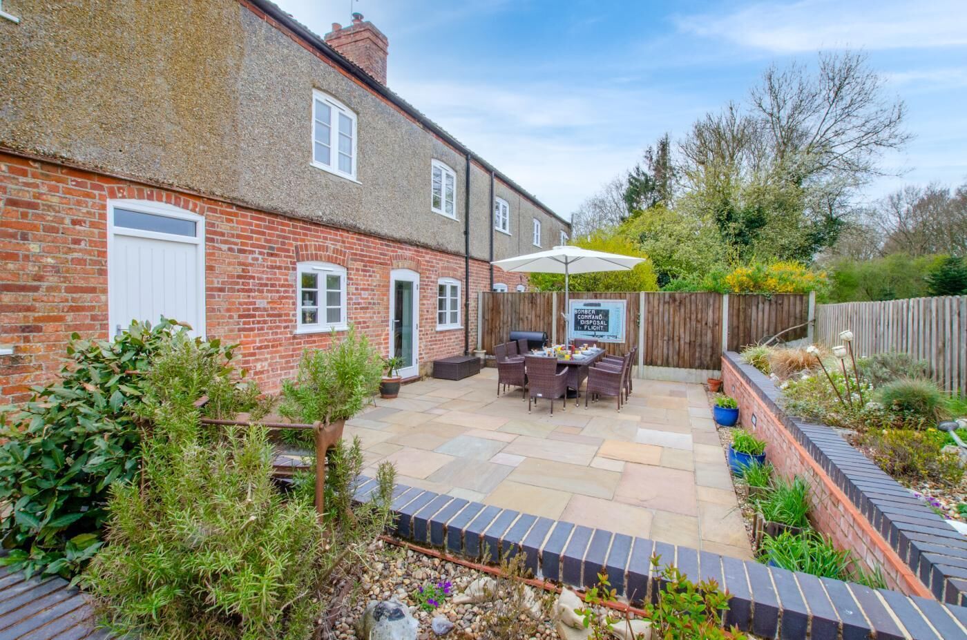 A patio with a table and chairs, a barbecue grill, and a wooden fence.