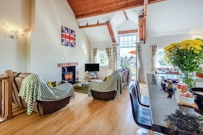 Una sala de estar acogedora con chimenea, dos sofás, un televisor y un comedor con mesa y sillas.