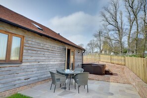 Une cabane en bois dotée d’un patio comprenant une table et des chaises, un jacuzzi et un mur en briques.