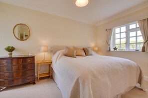 A bedroom with a large bed, a dresser, a bedside table, a mirror, and a window with curtains. - 1 Bed in Tenterden (oc-tn623) (Saint Michaels)
