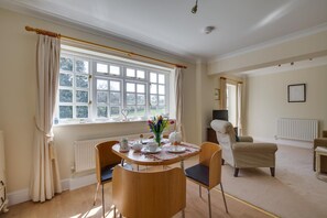 A dining area with a round table, chairs, a vase with flowers, and a radiator. - 1 Bed in Tenterden (oc-tn623) (Saint Michaels)