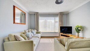 A living room with a sofa, a TV, and a plant. - 2 Bed in Wells-next-the-Sea (oc-1655) (Wells-next-the-Sea)