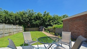 A backyard with a patio area, a brick wall, and a wooden fence. - 2 Bed in Wells-next-the-Sea (oc-1655) (Wells-next-the-Sea)