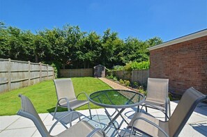 A backyard with a patio area, a brick wall, and a wooden fence. - 2 Bed in Wells-next-the-Sea (oc-1655) (Wells-next-the-Sea)