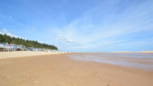 A beach with a row of beach huts and a clear sky. - 2 Bed in Wells-next-the-Sea (oc-1655) (Wells-next-the-Sea)