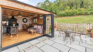 A cozy cabin with a wooden interior, a dining area, and a patio with outdoor furniture. - 1 Bed in Whitbourne (oc-s32935) (Whitbourne)