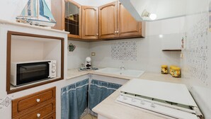 A kitchen with wooden cabinets, a microwave, a sink, and a small sailboat decoration. - Perla Marina Ground Floor Apartment with Wi-Fi and Air Conditioning (Trappeto)