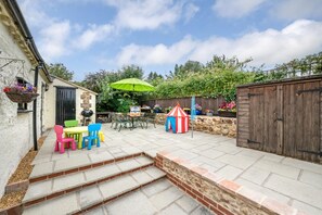 A patio with a table and chairs, a grill, a play tent, and a wooden fence. - 2 Bed in Colkirk (oc-1397) (Colkirk)