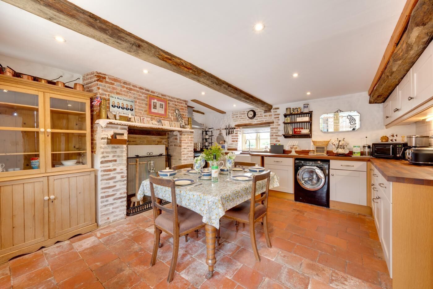 A kitchen with exposed brick walls, wooden cabinets, and a tiled floor.