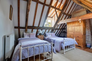 A bedroom with two beds, a wooden wardrobe, and a sloped ceiling with exposed beams. - 2 Bed in Colkirk (oc-1397) (Colkirk)