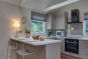 A modern kitchen with a central island, built-in appliances, and a large window providing natural light.